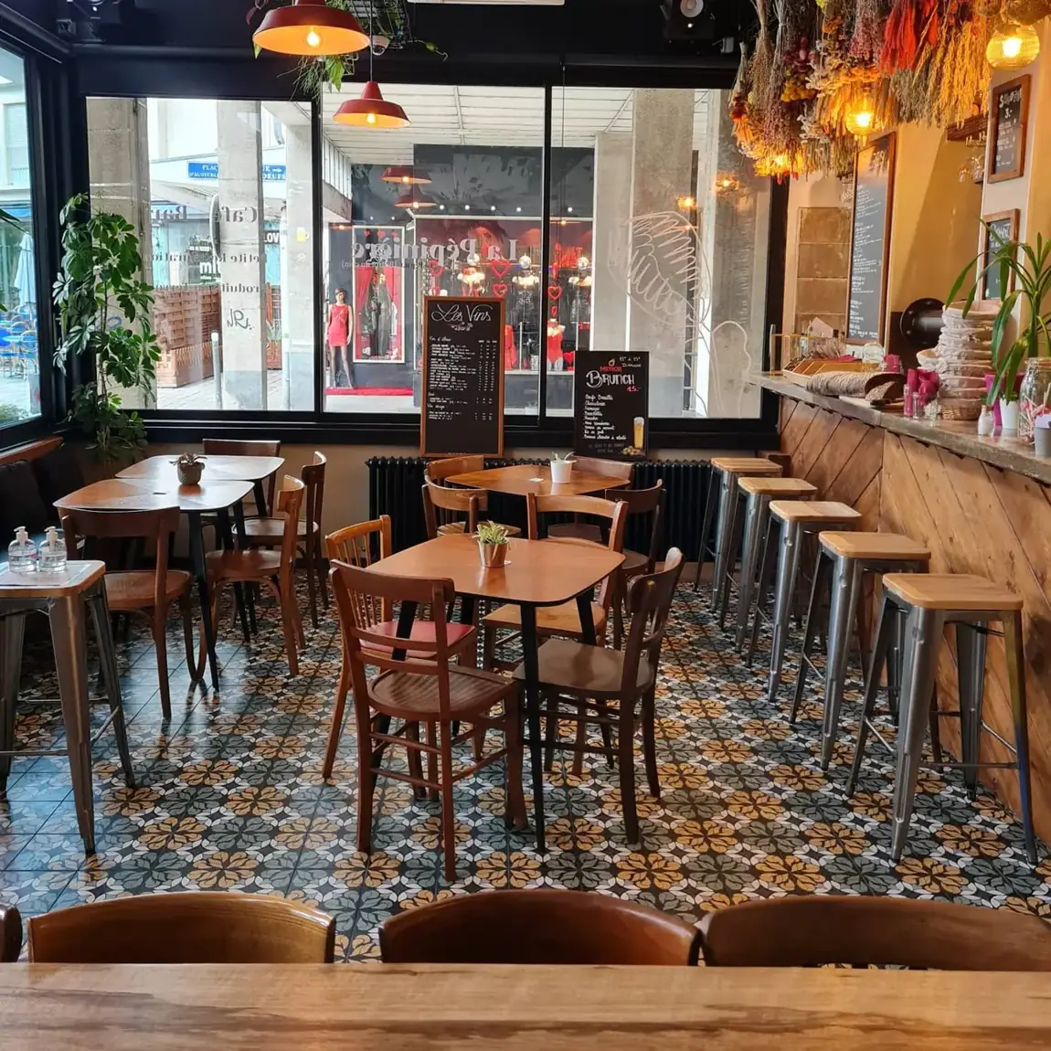 La salle : carreaux de ciment, tables en bois, comptoir